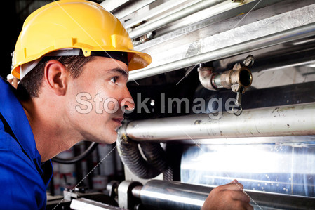 Industrial machine operator checking on machine while it's running