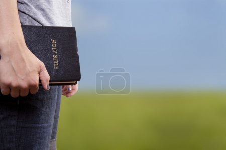 Standing Holding the Bible in a Field