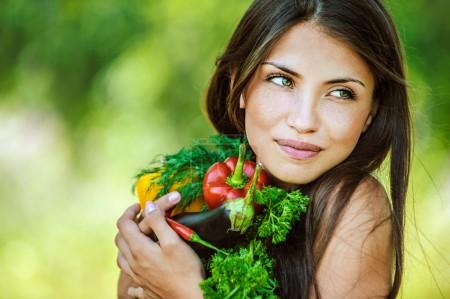 Woman with bare shoulders holding vegetable