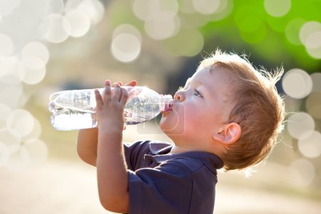 beautiful blonde child drink water outdoor