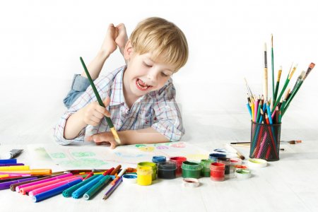 Happy child drawing with brush by multicolor paints