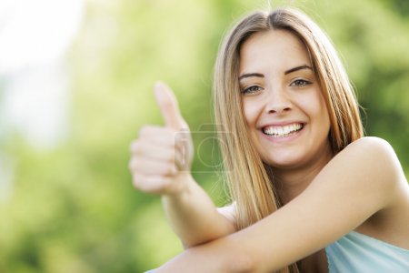 Happy young woman showing thumbs up sign