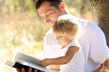 Young father with his daughter reads the Bible