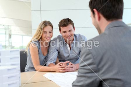 Couple in real-estate agency talking to construction planner