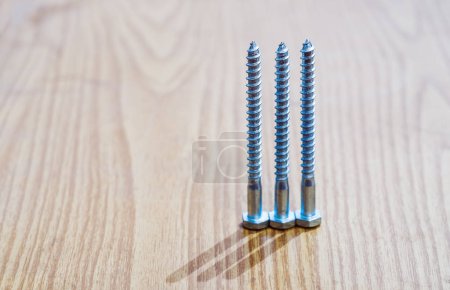 Three metal screws on a wooden surface