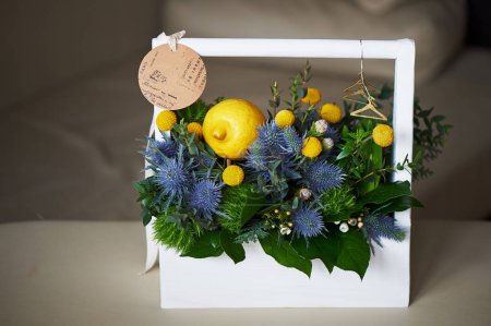 A spring bouquet in a white wooden box in the yellow-green spectrum. With lemon.
