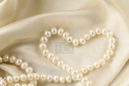 Pearl necklace in the shape of heart on silk fabric