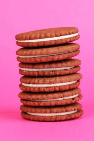 Chocolate cookies with creamy layer on pink background