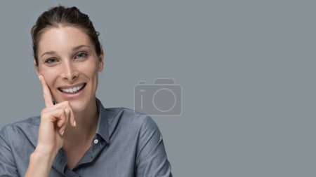 Confident attractive young woman posing with hand on chin and looking at camera