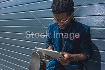 stylish african american man in blue jacket looking at tablet