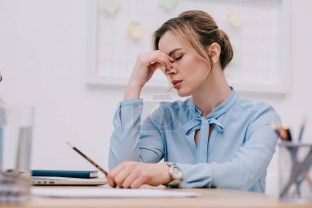 exhausted adult businesswoman sitting at workplace in office