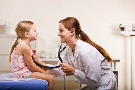 Doctor giving girl checkup in doctor office