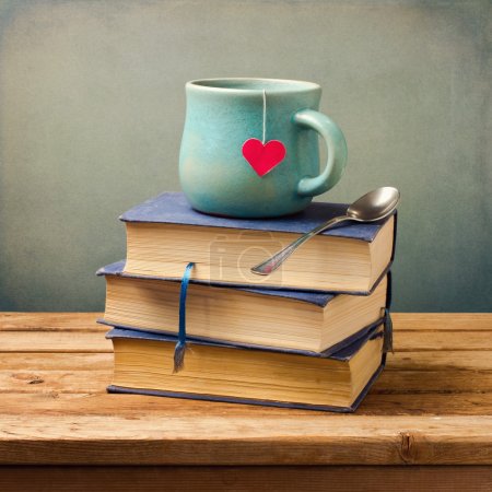 Old vintage books and cup with heart shape on wooden table