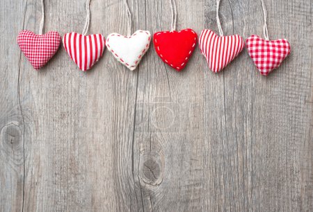 Red hearts hanging over wood background