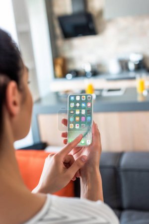 selective focus of woman using smartphone in kitchen