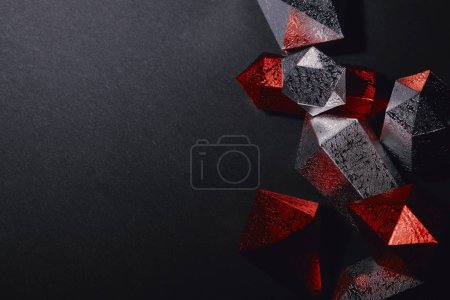 top view of shiny faceted red and silver gemstones on black background