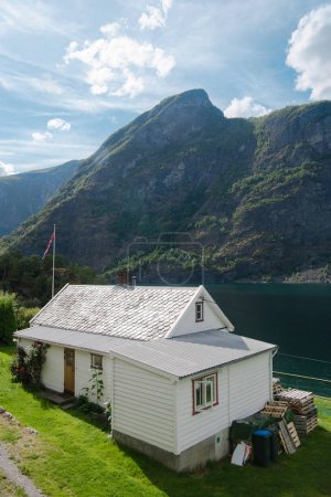 AURLANDSFJORD, FLAM, NORWAY - 27 JULY, 2018: high angle view of cozy white house and majestic mountains at Aurlandsfjord, Flam (Aurlandsfjorden), Norway