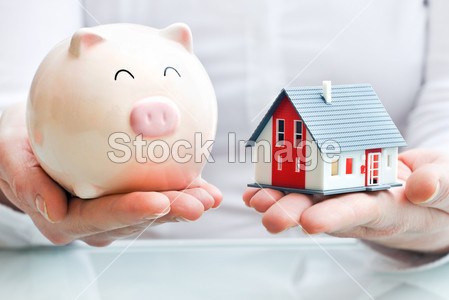 Hands with piggy bank and house model