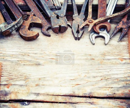 set of old rusty hand tools on a wooden table