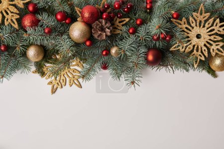 top view of fir twigs with Christmas toys and golden snowflakes isolated on white
