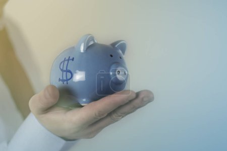 Blue piggy bank with fifty euros on a pink background. Symbol of  deposit, financial security. Selective focus.