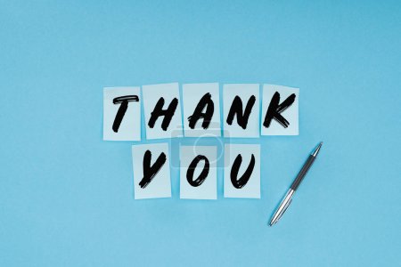 thank you wording on sticky notes and pen isolated on blue background