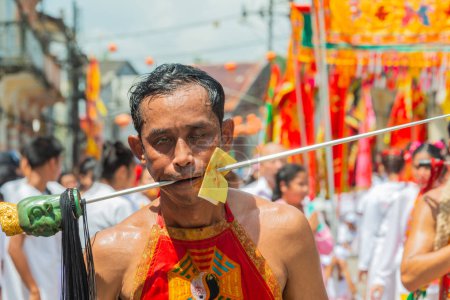 Phang Nga, Thailand - October 14, 2018: Man demonstrating sharp steel run through the mouth in vegetarian festival parade in Phang Nga, Thailand