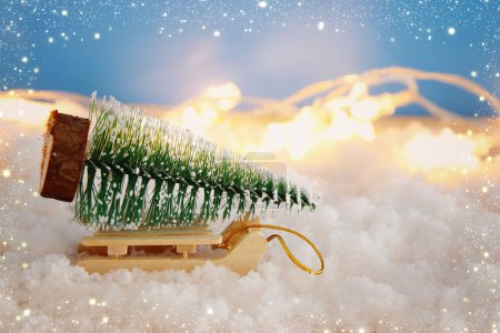 Image of christmas tree on the sled over snowy wooden table