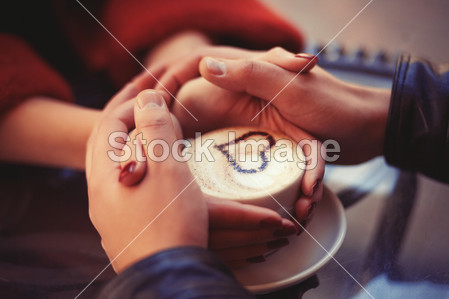 Four hands wrapped around a cup
