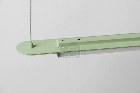 Green metal lamp hanging on gray wall background in studio