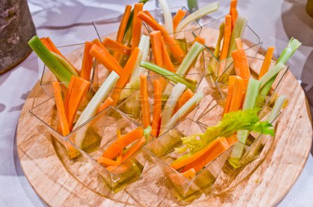 healthy appetizer, of vegetables with carrot, celery, olive oil, salt and pepper on wooden cutting board
