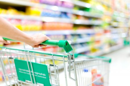 Cropped image of female shopper with cart at supermarket