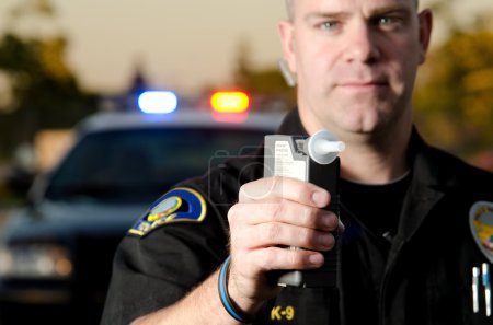 A police officer holds a breath test machine