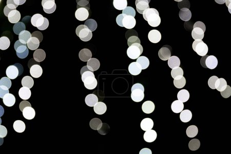 Bokeh white lights on black background, defocused and blurred many round light on background
