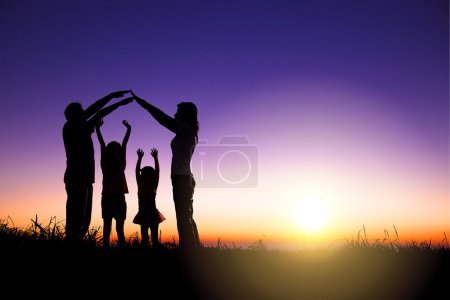 happy family making home sign on the hill with sunrise backgroun