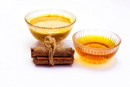 Cinnamon face pack isolated on white i.e. Cinnamon or tej powder well mixed with honey in a glass bowl and entire raw ingredients present on the surface,Used to clean acne and spots from skin.