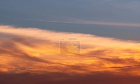 Beautiful blue and golden sky and clouds abstract background. Yellow-orange clouds on sunset sky. Warm weather background. Art picture of sky at sunset. Sunset and fluffy clouds for inspiration.