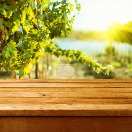 Empty wooden deck table over vineyard bokeh background