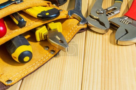 Necessary set of tools in the bag for plumbers on a wooden background.