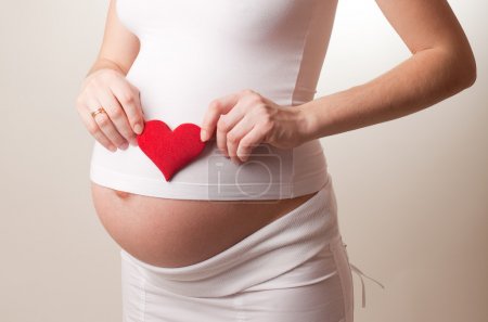 Pregnant woman put a toy heart