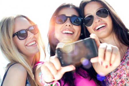 three friends taking photos with a smartphone