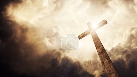 A wooden Christian cross with bright sun and clouds.