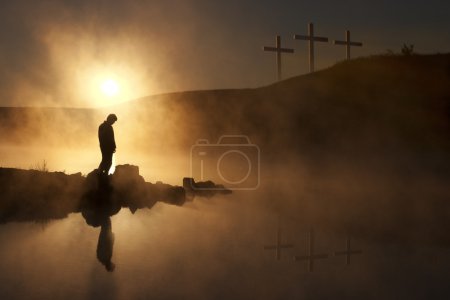Morning Sunshine and Fog Surround Silhouetted Hiker On Calm Lake