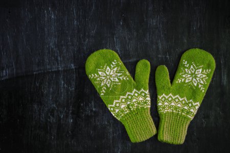 a pair of blue-green knitted mittens on a dark blue-green-brown wooden