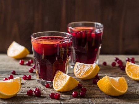 Traditional Christmas drink. Christmas hot mulled wine with oranges, cranberries and spices on a wooden table