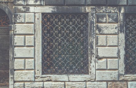 View of house exterior and window seen on a Venice street. Old building in Venice, Italy. Vintage window with rusty decorative bars.