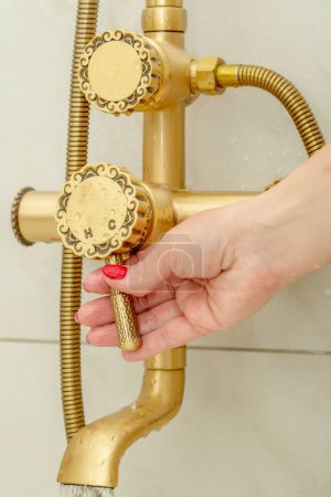 Famale hand switches a shower faucet in vintage style cold and h