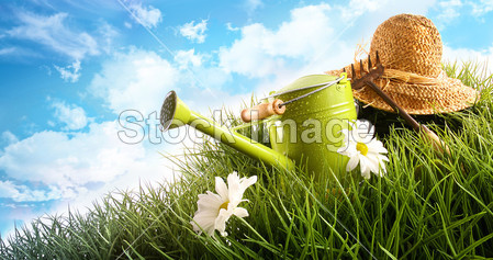 Water can and straw hat laying in grass