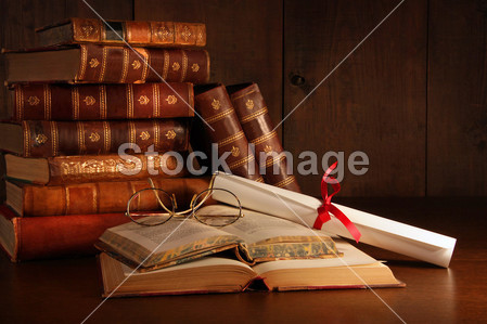Pile of old books with glasses on desk