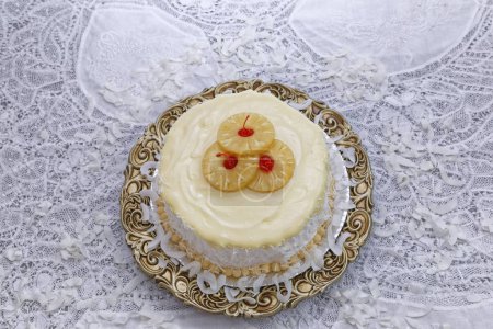 coconut cake with buttercream decorated with pineapple slices and cherries on brown plate
